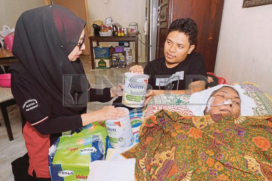 PENGASAS Cancer Survivor Malaysia (CSM) Zuraini Kamal (kiri) menyampaikan bantuan  kepada Mohd Khairul   (kanan) di rumahnya.