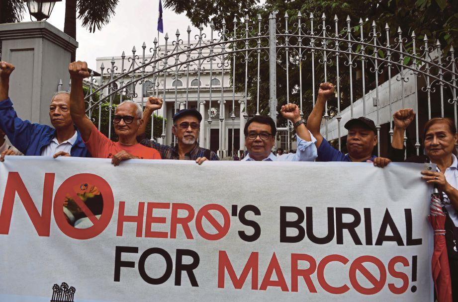 AKTIVIS dan mangsa undang-undang tentera memegang sepanduk di hadapan bangunan Mahkamah Agung di Manila untuk membantah rancangan mengebumikan bekas presiden negara itu, Ferdinand Marcos,   di makam pahlawan, semalam. - AFP  