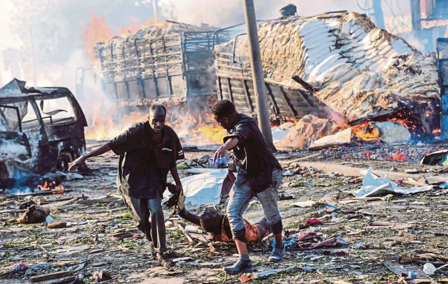 DUA lelaki menarik mayat seorang mangsa yang maut dalam serangan bom trak di Mogadishu kelmarin. - AFP