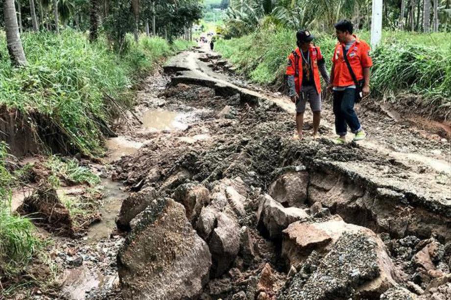 SUKARELAWAN membantu membersihkan jalan di daerah Bang Saphan,  di Prachuap Khiri Khan yang rosak akibat banjir dan hujan lebat.  - Bangkok Post 