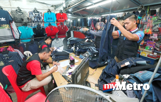 ANGGOTA Kementerian Perdagangan Dalam Negeri Koperasi dan Kepenggunaan (KPDNKK) Pahang memeriksa dan merampas seluar serta  kasut yang tidak mempamerkan penandaan harga. FOTO Zulkepli Osman