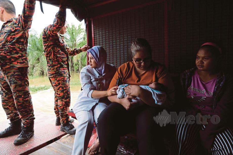 DOKTOR Klinik Kesihatan Tanjung Gemok, Dr Monysyha Atri (dua dari  kanan) meriba bayi berusia 21 hari, Nor Syakina Osman keluar dari kawasan banjir bersama ibu bayi berkenaan,  Rohayani Ali menggunakan trak Jabatan Bomba dan Penyelamat Malaysia (JBPM) Rompin, semalam. 