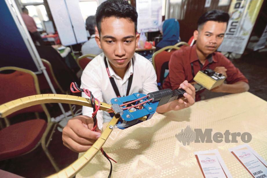 MUHAMMAD Fadhlan (kiri) dan Muhamad Ilham Hakimi bersama inovasi alat menangkap ular Snake Shock Stick yang dicipta. 