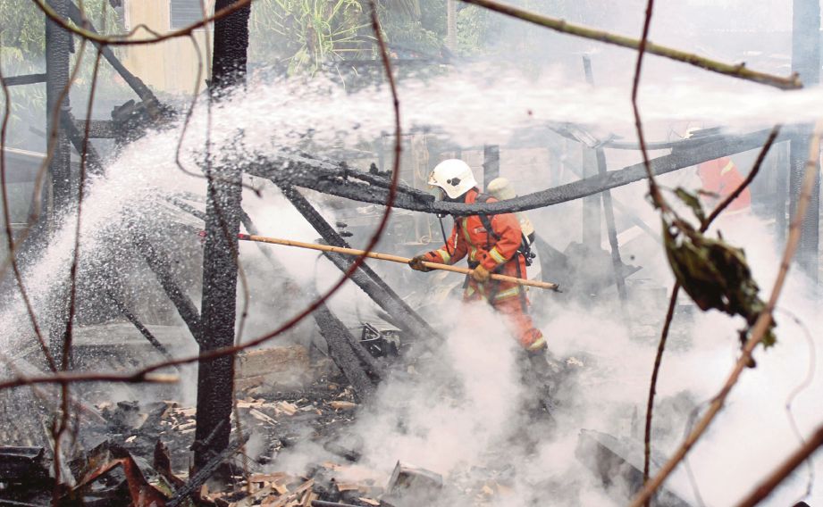 Anggota bomba  bertungkus-lumus memadamkan kebakaran  rumah kayu dua tingkat di Kampung Wakaf Mek Zainab.