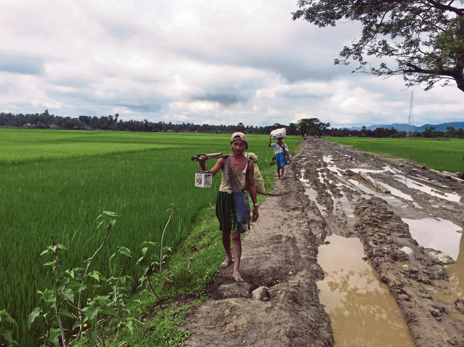 PENDUDUK membawa barangan milik mereka ketika berpindah ke kampung lain di Maungdaw, Rakhine.