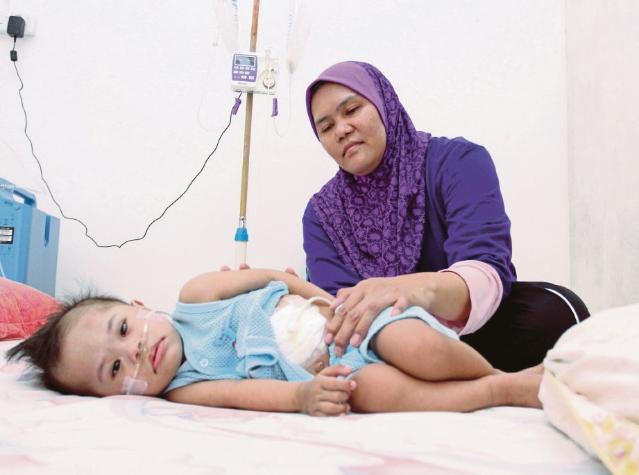  Roslina  bersama  Mohammad Iman yang menghidap sakit paru-paru kronik  di rumah mereka di Kampung Chenderung Kubu, Tumpat.