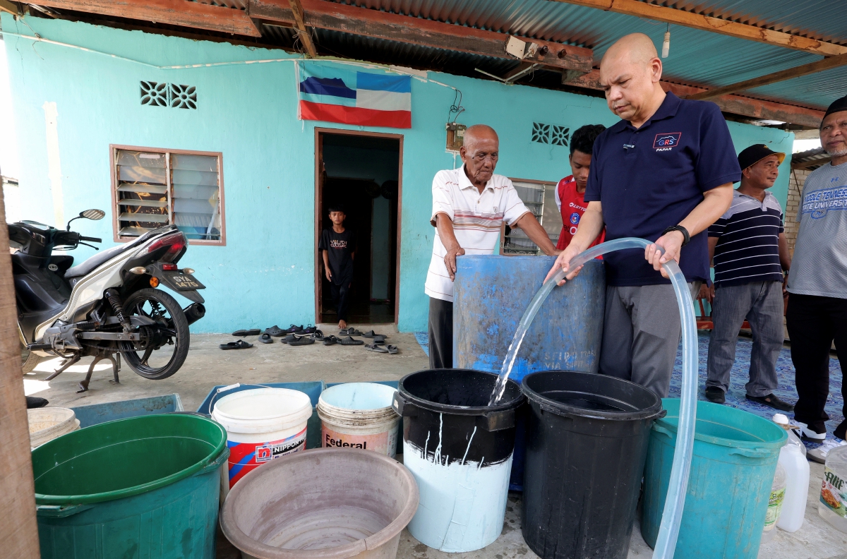 ARMIZAN mengisi air bersih ke dalam bekas yang disediakan penduduk kampung ketika membuat penghantaran air bersih ke Rumah PPRT Kampung Kuala Dalam Papar hari ini. FOTO Bernama.