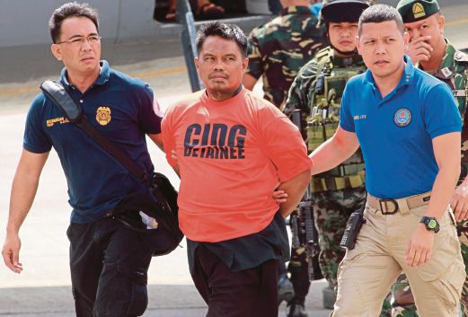 ALI (tengah) dikawal anggota polis ketika tiba di Pangkalan Udara Villamor, Manila, semalam.