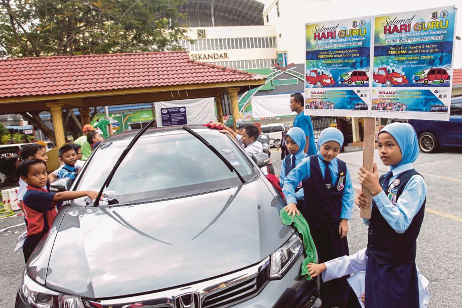 PELAJAR SK Setiawangsa membersihkan kenderaan guru pada program Servis Cuci Kereta Percuma.