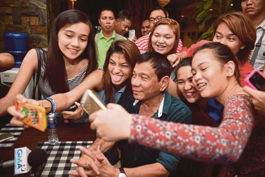 DUTERTE berselfie bersama penyokongnya selepas sidang akhbar pertamanya sejak  memenangi pilihan raya presiden Isnin lalu di sebuah restoran di bandar Davao, lewat kelmarin.