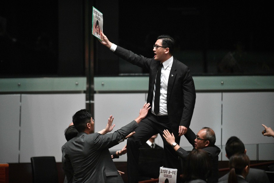 AHLI Parlimen prodemokrasi, Lam Cheuk-ting berdiri atas meja memprotes sebelum Carrie meninggalkan dewan. FOTO AFP