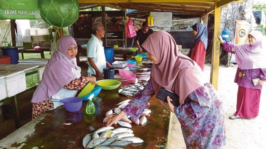 PENIAGA ikan melayan pelanggan di kedainya, di Kuala Terengganu.