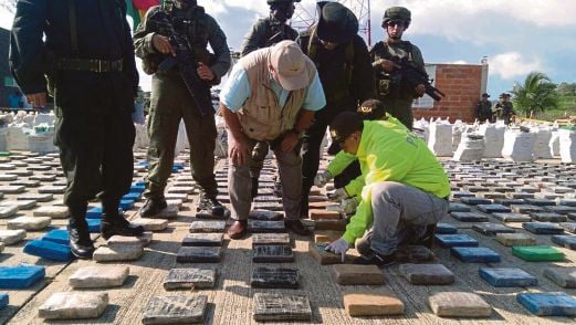 MENTERI Pertahanan Luis Carlos Villegas (tengah) memeriksa bungkusan kokain yang dirampas.