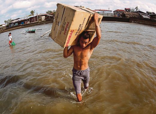 SEORANG penduduk kampung mengangkat barangan miliknya sambil meredah banjir di wilayah Sorsogon, selatan Manila, semalam. 
