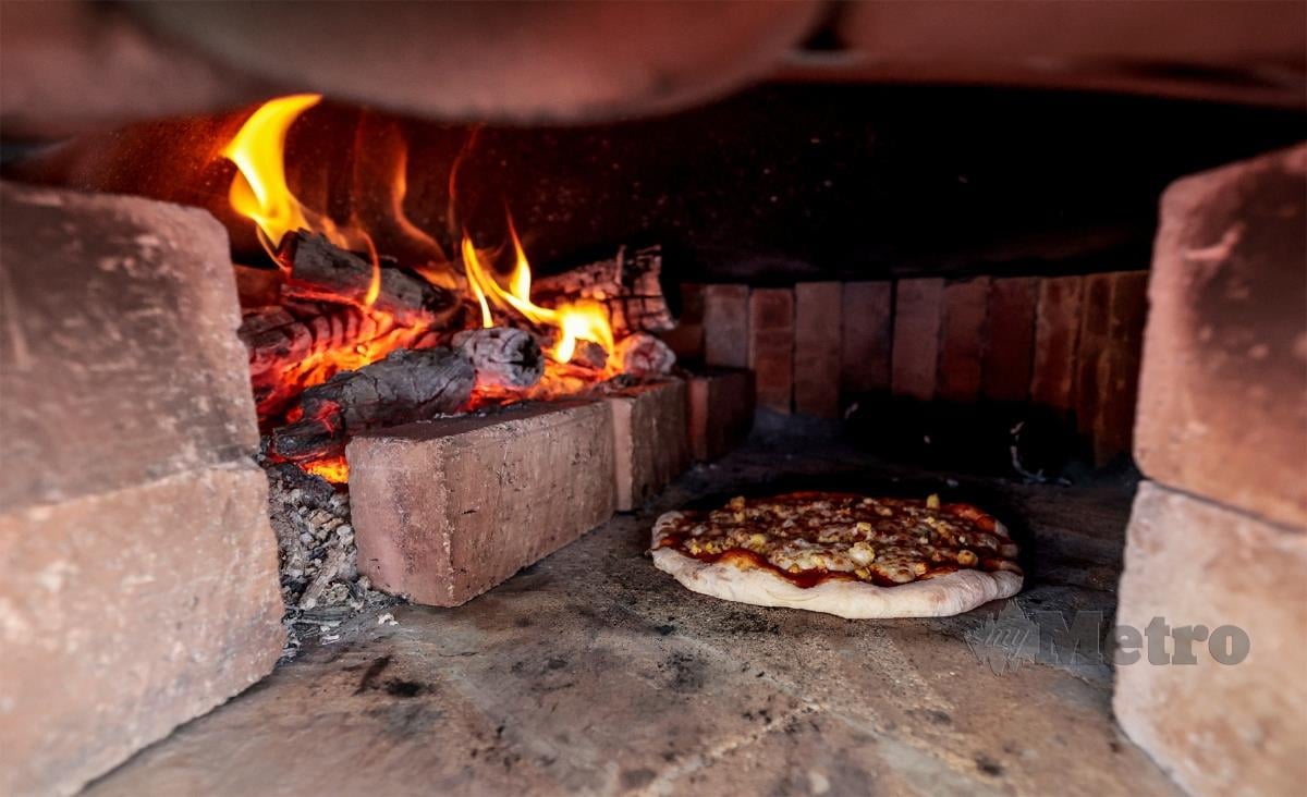 HAMZAH  sibuk menyediakan piza menggunakan dapur kayu api.