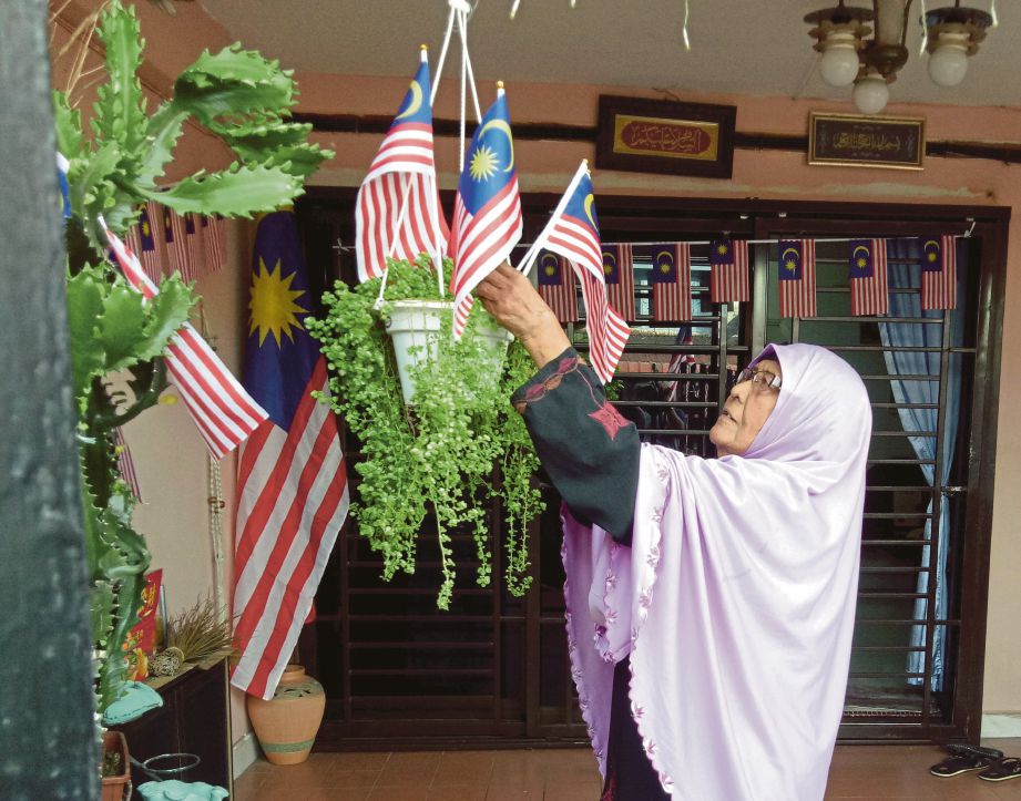 ROGAYAH tekun memasang bendera yang menghias kediamannya di Taman Desa Harmoni, Johor Bahru.