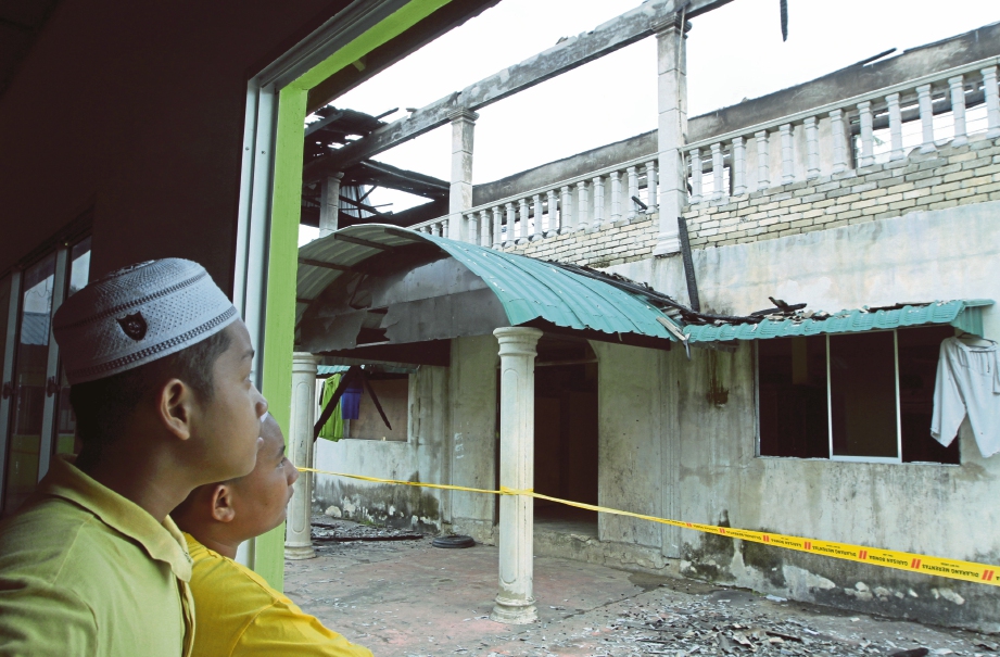 PELAJAR melihat bangunan asrama yang musnah dalam kebakaran.