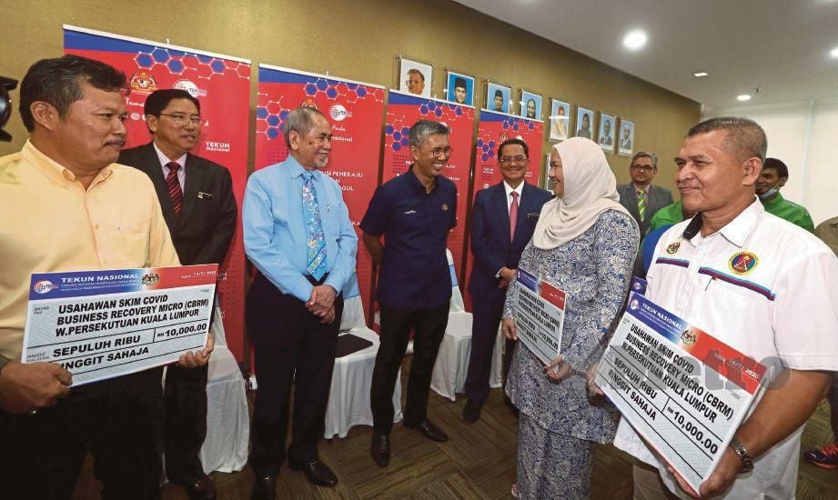 TENGKU Zafrul (tengah) bersama Menteri Pembangunan Usahawan dan Koperasi, Datuk Seri Wan Junaidi Tuanku Jaafar (tiga dari kiri) bersama penerima sumbangan usahawan skim CBRM Wilayah Persekutuan, semalam.