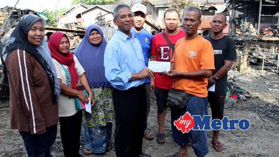 NIK Mohd Azlan (empat kiri) menyampaikan sumbangan kepada mangsa kebakaran di Lorong Chicha, Berek 12. FOTO Nik Abdullah Nik Omar