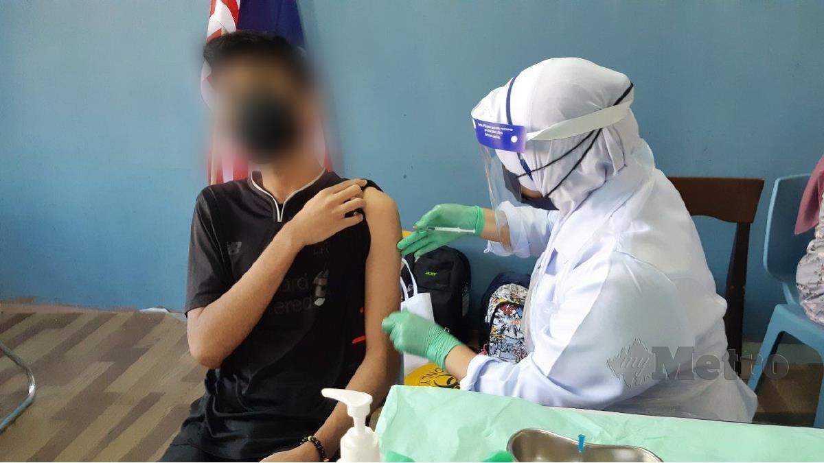 SEORANG remaja menerima suntikan vaksin Covid-19 pada program pemberian vaksin pada gelandangan dan komuniti Lorong Wang Ah Jang dan Jalan Pasar Besar. FOTO Mohd Rafi Mamat