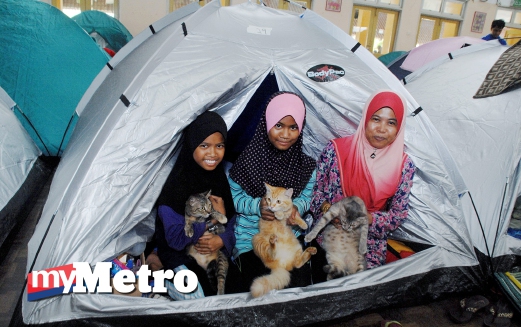 MANGSA banjir, Zamariah Mat Said, 46, bersama anaknya Nur Alisha Shamsumajidi, 11, (tengah) dan Nur Alia Shamsumajidi, 12, (kiri) menunjukkan kucing peliharaan mereka yang diselamatkan di pusat pemindahan sementara di Dewan Sekolah Menengah Kebangsaan Meru, Klang. FOTO Nazran Jamel