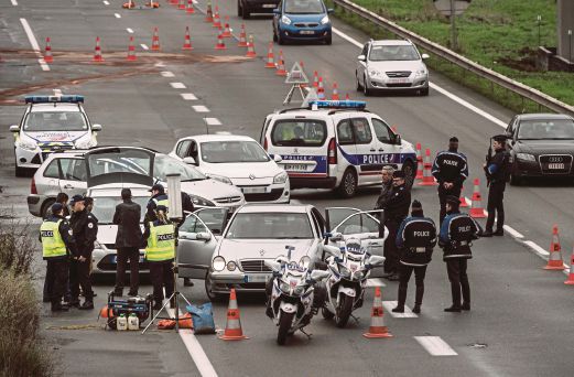 ANGGOTA polis Perancis memeriksa identiti pemandu kenderaan dalam satu sekatan jalan raya di Paris, semalam