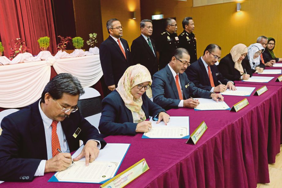 Zainal  (berdiri dua kiri) menyaksikan pegawai tertinggi LPP menandatangani dokumen ikrar bebas rasuah