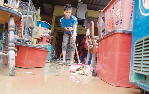 KUSHAURY Majid membersihkan halaman rumah yang dilanda banjir lumpur.
