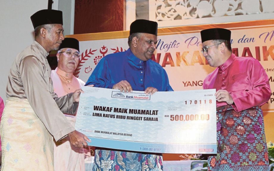 DR Tengku Muhammad Fa-iz (kanan) menerima replika cek berjumlah RM500,000 sumbangan wakaf daripada Bank Muamalat yang disampaikan  Mohd Redza.