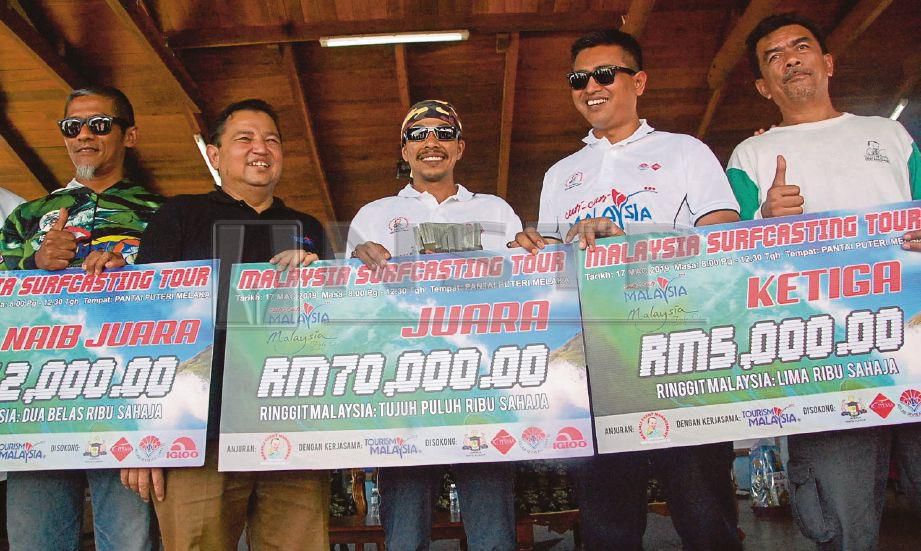 MOHD FAIZUL (tengah) berkongsi kegembiraan muncul johan Malaysia Surfcasting Tour dengan membawa pulang RM70,000 di Pantai Puteri, Tanjung Kling. 