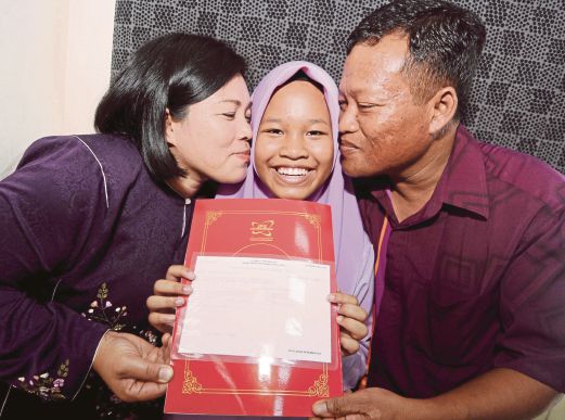 Natasya    mendapat ciuman tahniah daripada ibu bapanya selepas pengumuman keputusan UPSR 2015.