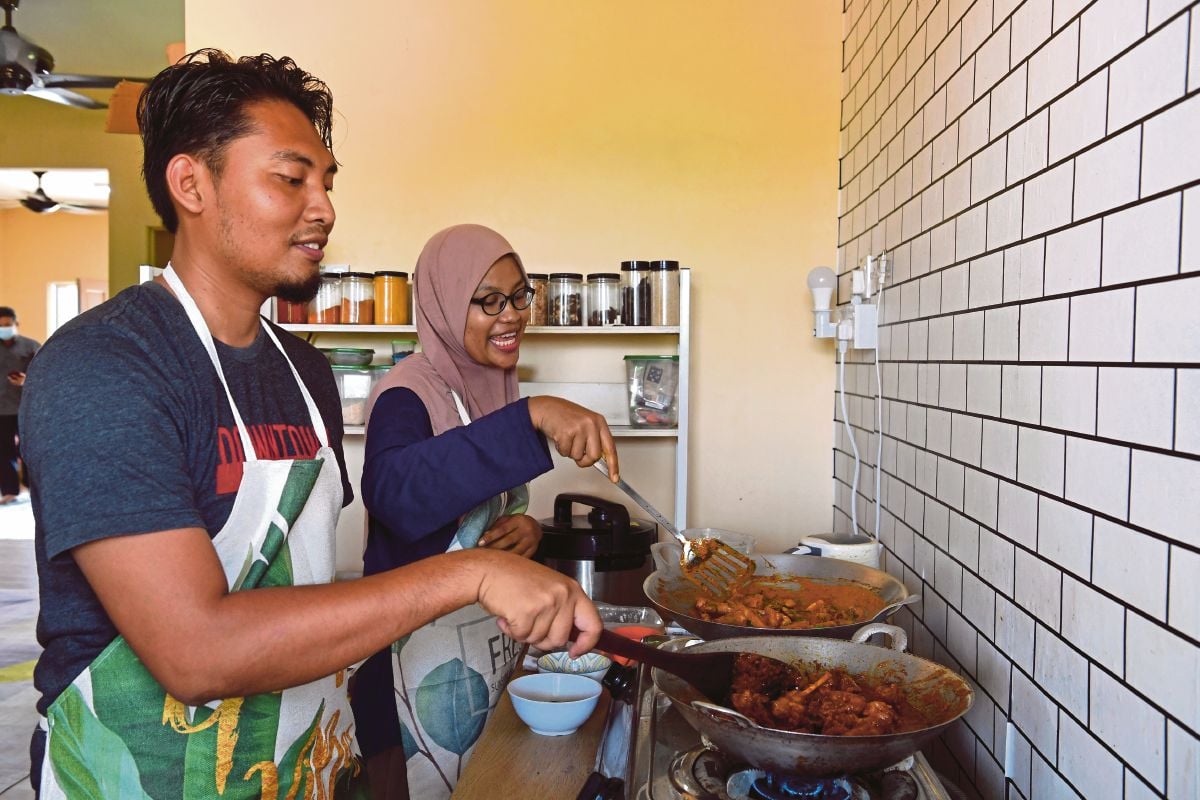 ZAIN ‘Aliuddin   membantu isterinya memasak rendang arnab di rumah mereka di Kampung Hulu Teris. FOTO BERNAMA