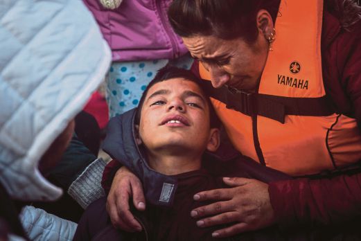 SEORANG budak dibantu ibunya selepas pengsan keletihan setibanya mereka di pulau Lesbos dari Turki.