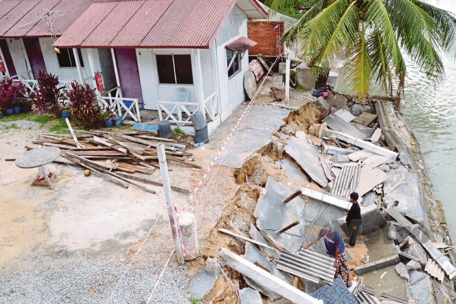 NOR Afandi   mengemaskan runtuhan tembok penahan ombak dan anjung chalet milik ibu dan kakaknya di Kampung Pengkalan Balak, dekat Alor Gajah. 
