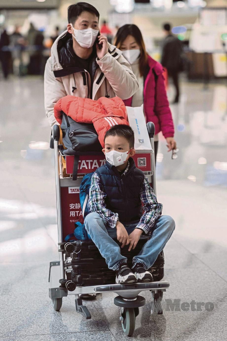 SATU keluarga memakai topeng muka untuk pulang ke kampung halaman bagi sambutan Tahun Baharu Cina sebaik sahaja mendaftar masuk di Lapangan Terbang Daxing, Beijing.  