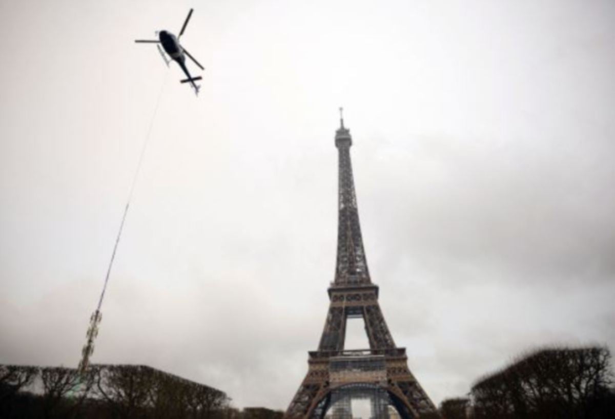 HELIKOPTER mengangkut antena baharu untuk dipasangkan ke Menara Eiffel, Selasa lalu. FOTO Reuters