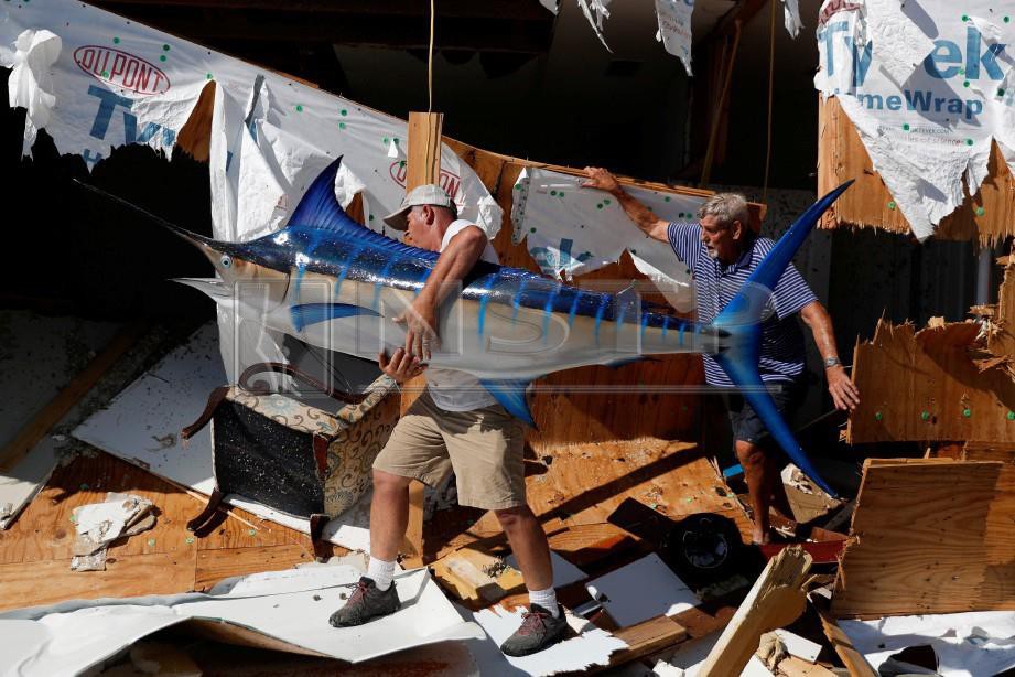 PENDUDUK membersihkan kediaman yang musnah dalam taufan itu di Mexico Beach. - Reuters
