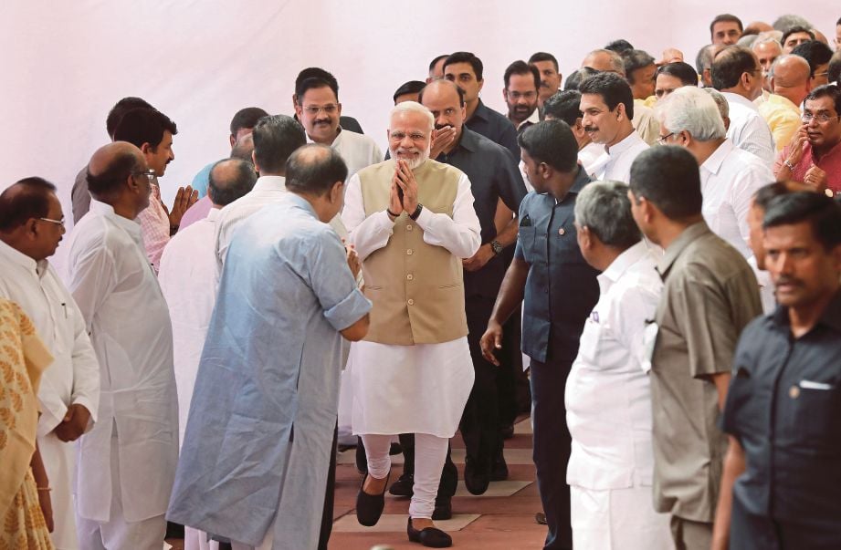 MODI (tengah) memberi hormat kepada  anggota Parlimen selepas dia mengundi di Dewan Parlimen di New Delhi, semalam.  - EPA