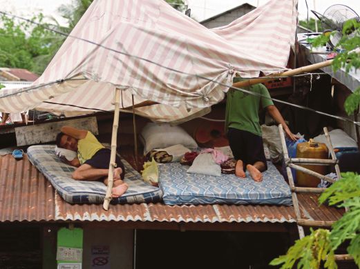 PENDUDUK di bandar La Paz, selatan Manila  berlindung di bumbung rumah mereka selepas kawasan berkenaan di naiki air.  
