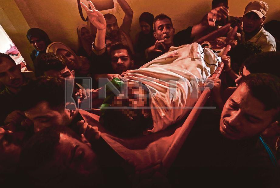 PENDUDUK membawa jenazah pemuda yang terkorban dalam serangan udara Zionis. FOTO/AFP 