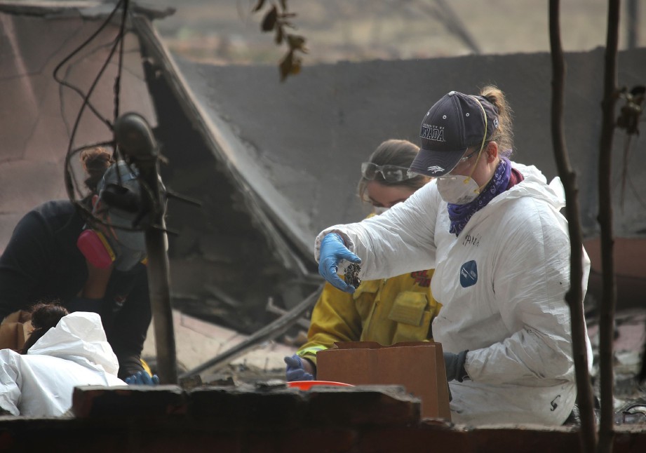 PENYELAMAT menyimpan sisa tulang dalam beg selepas menemuinya di dalam rumah yang musnah dalam kebakaran Camp Fire di Paradise. - AFP
