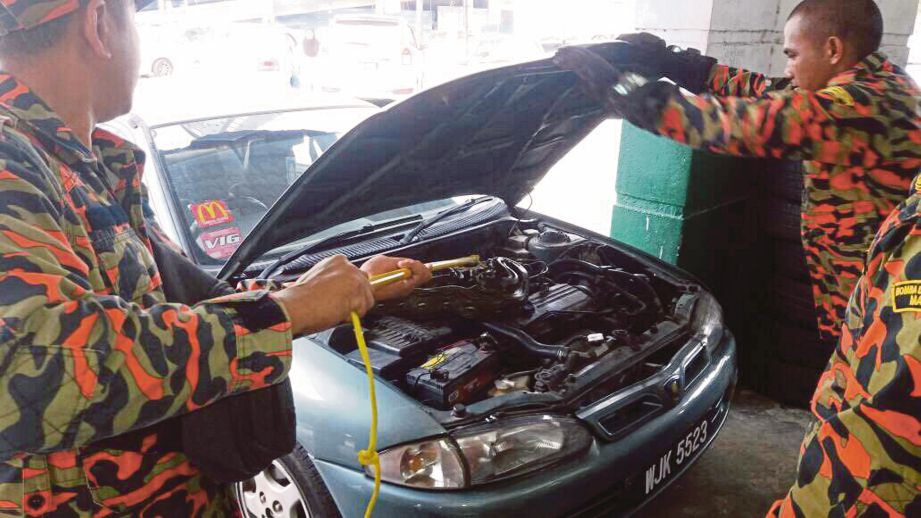 ANGGOTA bomba   menangkap ular di ruang  enjin kereta di bengkel   di Seksyen 8, Bandar Baru Bangi, semalam. 