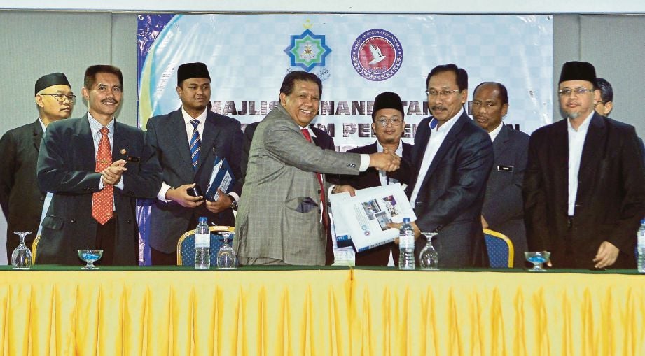  BAKHTIAR (hadapan dua dari kanan) dan Dr Abd Halim bertukar dokumen perjanjian pada Majlis Menandatangani MoU Pusat Pemulihan Baitul Islah MAIS dan AADK di Hotel Aliya, Klang.
