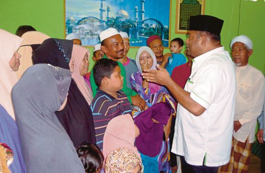 ABDUL Azeez (dua dari kanan) berbual dengan Abdul Wahab ketika menziarahi keluarga berkenaan di Baling. 