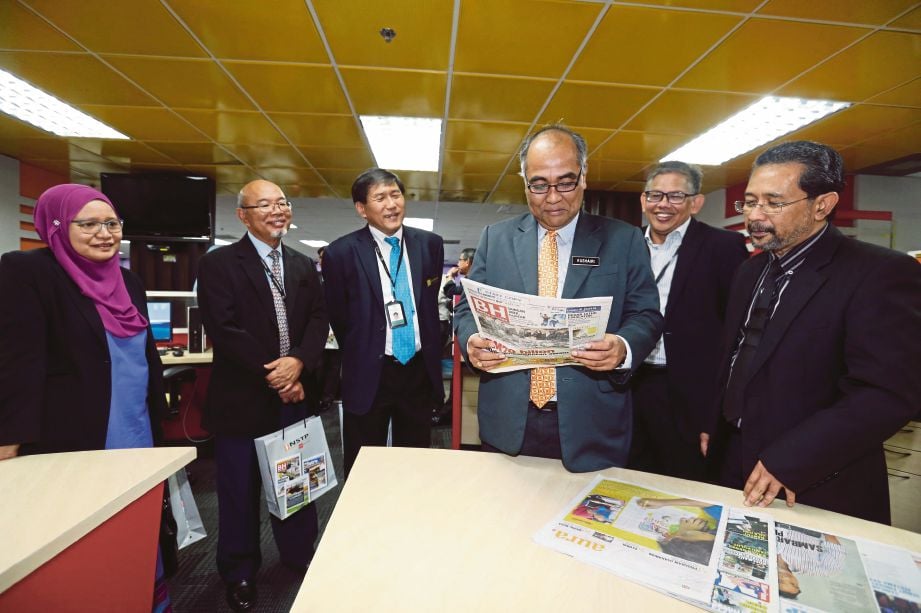 AHMAD Kushairi (tiga dari kanan) melihat suratkhabar Berita Harian (BH) sambil diperhatikan  Abdul Jalil  (dua dari kanan), Mahfar (kanan) dan Pengarah Kejuruteraan dan Pemprosesan MPOB, Dr Lim Weng Soon (tiga dari kiri) selepas majlis menandatangani Kontrak Penerbitan Berita Sawit 2016/2017 di Balai Berita, Bangsar.