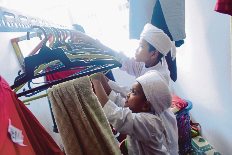 Pelajar makan dan menyusun pakaian di ruangan yang ada di Madrasah Al-Huffaz Wal-Ulum, Puncak Alam.