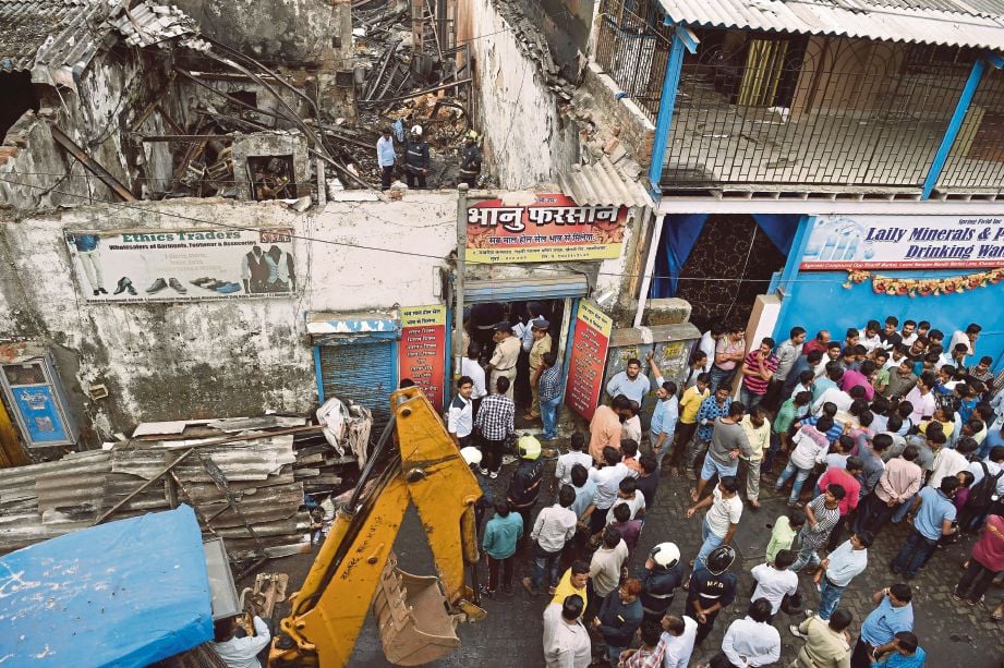 ORANG ramai berkumpul melihat kedai yang terbakar dan mengorbankan 12 orang di Mumbai, India semalam. - AFP
