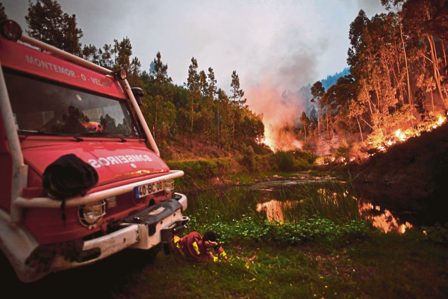 ANGGOTA bomba yang kepenatan berehat di sebelah kereta bomba mereka ketika operasi memadamkan kebakaran hutan di Penela, Coimbra di tengah Portugal, semalam.  - AFP  
