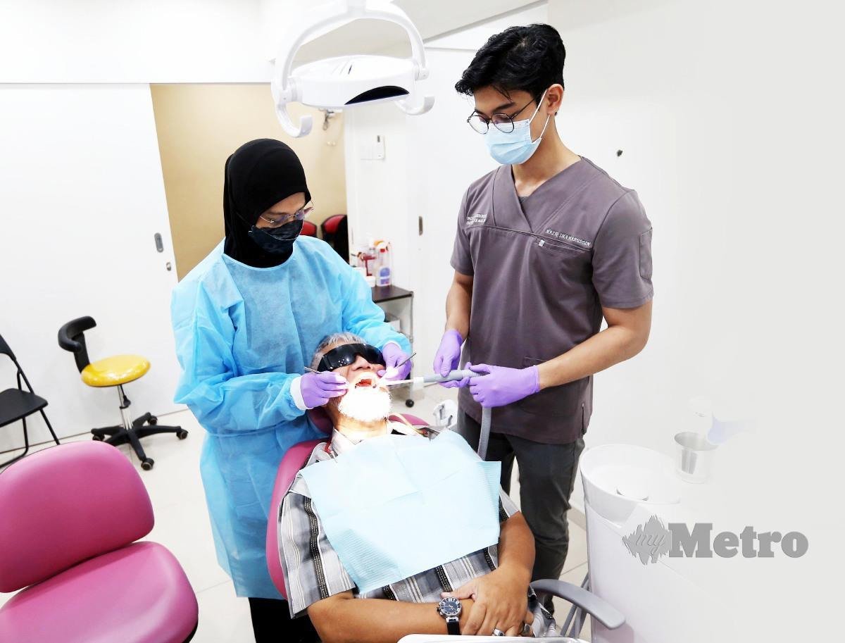 Dr Nor Azlina Mohd Amin dibantu anak membuat rawatan di klinik. 