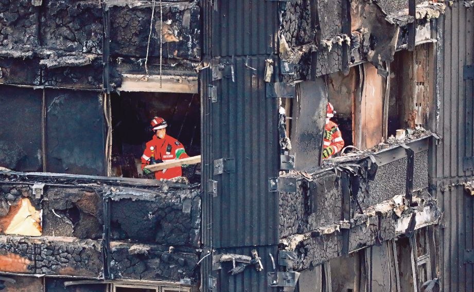 ANGGOTA bomba memeriksa tingkat pertengahan bangunan Grenfell Tower yang musnah dalam kebakaran 14 Jun lalu. -AFP 